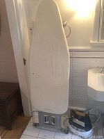 White Rowenta ironing board with cover and metal folding legs.