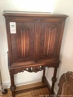 Full front view of music cupboard showing doors, carved panels, stand