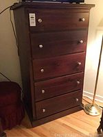 Full front view of dark brown wood dresser showing all five drawers and metal knob pulls.