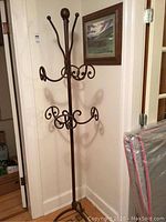 Full height view of the iron coat rack showing all hooks and scrollwork details.