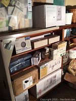 Multiple boxed lighting and bathroom fixtures stacked on wooden shelves
