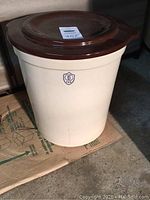 Full view of cream colored 5 gallon stoneware crock with brown lid on top showing overall shape and size.