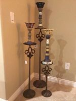 Three tall metal candle stick holders of varying heights placed side-by-side, showing overall size and design