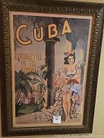 Framed vertical poster depicting a Cuban holiday scene with a woman in a ruffled dress and tropical background, framed in an ornate gold-colored frame.