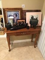 Photo of wooden entry table showing Asian art and decorative items on top