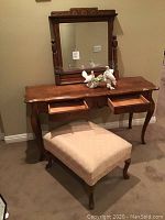 Full view of vintage vanity table with drawers open, attached mirror, cushioned stool, and dove figurines on top
