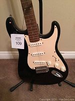 Front view of the black Squier electric guitar, showing body, pickguard, pickups, and control knobs.