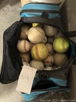 Open soft sports bag filled with used baseballs showing various degrees of dirt and wear.