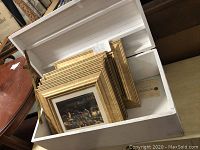 White wooden chest box open with 6 gold framed pictures inside