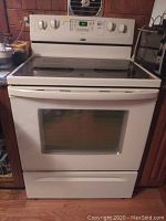 Full view of white Whirlpool AccuBake electric stove showing black glass-ceramic cooktop, oven door with window, and control knobs.
