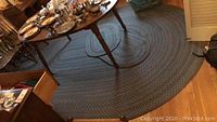 Large oval braided rug under dining table with visible wear and stains