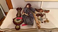 Full view of all items including Taylor barometer with thermometer, doll, watch, compass, shoe forms and small accessories spread on table