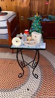 Overview of the lot showing black metal framed mosaic side table with items on top including ceramic Christmas tree, electric window candle, soap dishes and small ceramic decor.