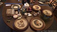 Overview of the lot on a table showing plates, figurines, bell, candles, and musical figure