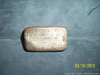 View of the front engraved surface of the metal matchbox sample showing engraved text identifying it as a sample by G.W. Gill & Ax Tobacco Works of Baltimore Maryland with patent date 1888.