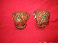 Pair of Bossons bulldog head wall plaques displayed on red background, showing details of both heads and collars.