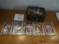 Five Metallic Impressions Babe Ruth cards in protective sleeves arranged on a wooden surface next to the custom metal box.