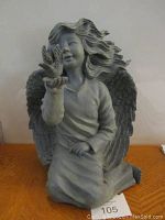 Front view of the seated angel statue showing detailed flowing hair, wings, and dove in palm.