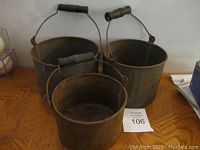 Set of three antique metal buckets seen from above, showing interior and wooden handles