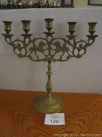 Front view of the brass candelabra showing the five candle holders and lion cutout design on the arms.