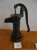 Front angled view showing overall build and height of the cast iron hand water pump with curved handle and spout.