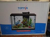 Box of Top Fin 20 gallon Essential aquarium starter kit showing tank filled with water and fish decorations printed on front.