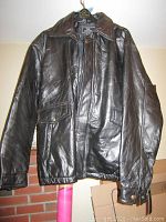 Front view of the black genuine leather men's jacket showing zip and snap button closure, flap pockets, and collar.