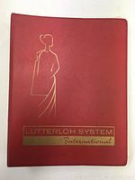 Front cover of the red Lutterloh System International binder with gold embossed art and text