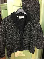 Full view of the vintage wool jacket showing the black collar and textured black and white speckled wool fabric.