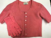 Pink ribbed wool angora sweater with matching gloves laid flat. Sweater has five buttons down front and a scoop neckline.