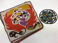 Rectangular placemats with large abstract red, orange, purple, yellow, black design on beige linen.