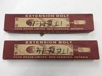 Two unopened red boxes labeled Extension Bolt by Hahn Brass Limited, New Hamburg, Ontario, with handwritten markings on top.