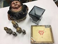 Wide view of ceramic figurine, gray glass vase, six salt and pepper shakers, and vintage box on white surface