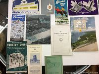 Overview photo showing all 11 brochures arranged on a surface, visible titles include Universal International, New York State Thruway, Visit St. Louis, Nova Scotia, Virginia Capitol, and more.