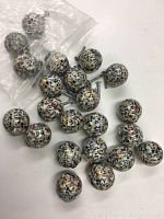 Photo showing 23 spherical drawer pulls with terrazzo pattern in a resealable plastic bag and spread out, displaying metal screw backs.