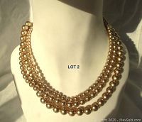 View of the triple strand faux pearl necklace displayed on a bust showing the graduated pearl sizes and layered design.