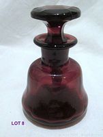 Front view of vintage perfume bottle showing the deep eggplant and brown color, rounded shape, and faceted stopper on top.