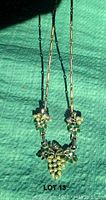 Full necklace showing gold-tone chain and grape cluster faux pearl pendant on green background.