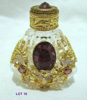 Clear glass miniature perfume bottle with gold filigree and purple gems, shown at an angle to display front and side details.