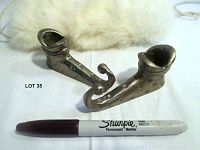Pair of silver jester shoe candle holders next to marker for size reference.
