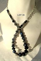 Front view of the necklace displayed on a mannequin bust showing the faceted black and blue crystals with silver-tone chain and beads.