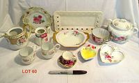 Front view of all china pieces including cups, saucers, teapot, creamer, sugar bowl, heart-shaped dish and platter.