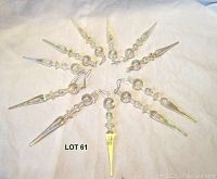 Circle arrangement of 11 clear acrylic icicle drop decorations showing pointed tapered ends and spherical segments with metal hooks.