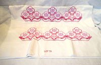 Wide view of two heavy cotton pillow cases featuring embroidered floral designs in pink and red thread arranged horizontally on white fabric.