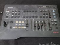 Full view of black Panasonic WJ-AVE5 AV mixer showing all control buttons, sliders, and joystick.