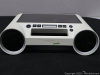Front angled view of the white and black Eton Rukus Solar boombox showing dual round speakers, LCD display, buttons, and solar panel on top.