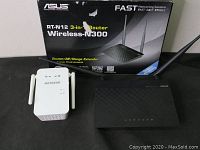 Photo of Asus RT-N12 Wireless-N300 router with descriptive box and Netgear WiFi extender placed side by side.