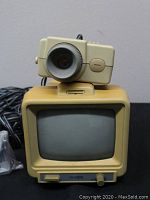 Front view of vintage CC TV camera mounted on CRT monitor, showing screen and camera lens