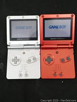 Both silver and red Game Boy Advance SP consoles powered on showing the Nintendo boot logo on screen.