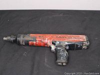 Full side view of Hilti DX 36 M tool showing overall wear and paint splatter.